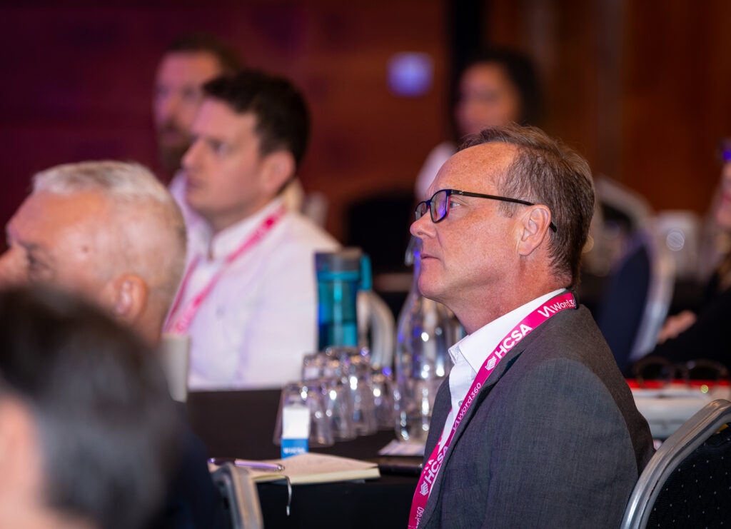 Mark Kevlin in the audience listening attentively at the speaker.