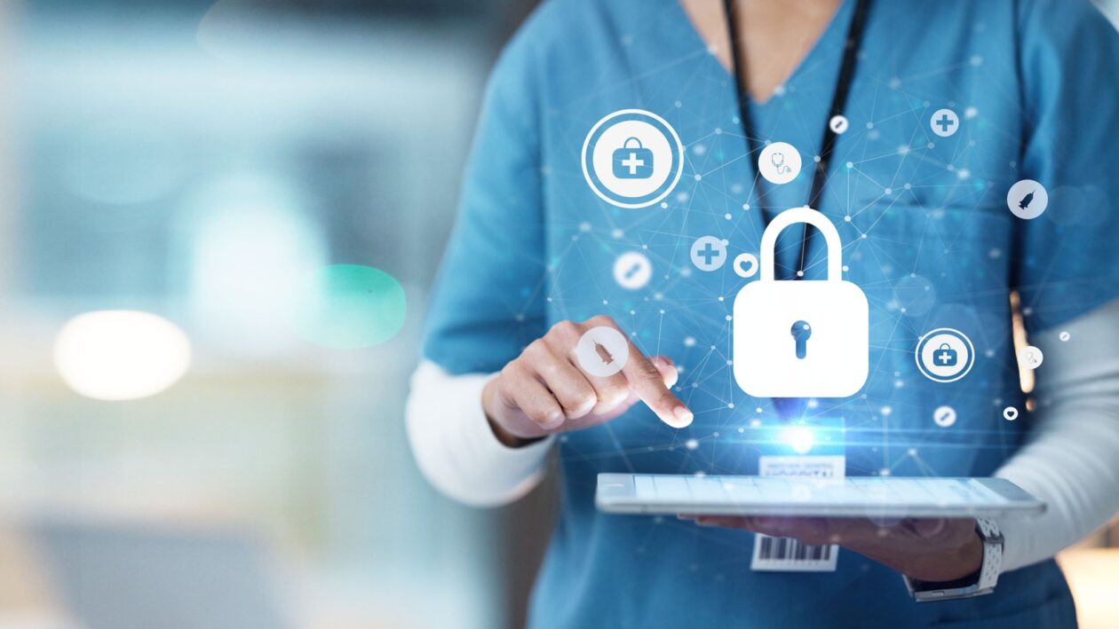 A medical practitioner is holding a tablet face-up. Security icons are hovering over the screen.