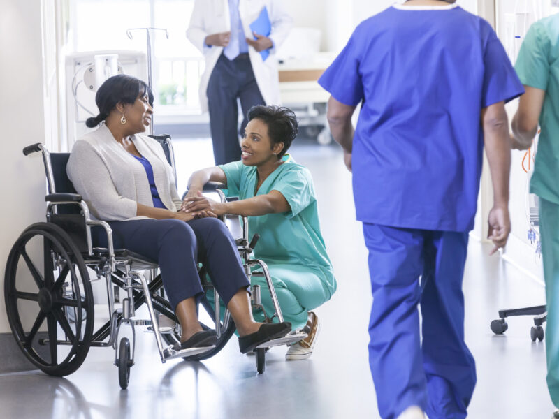 Doctor greeting a patient in a wheelchair in a hospital ward
