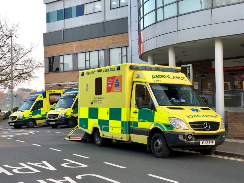 An ambulance driving past a hospital entrance